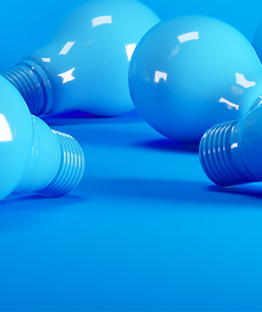 Close up of four blue light bulbs laying on a blue floor.