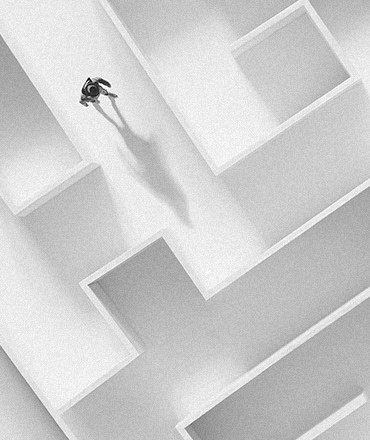 A person, alone, walking in the middle of complex, white maze representing a poor digital experience for b2b buyers