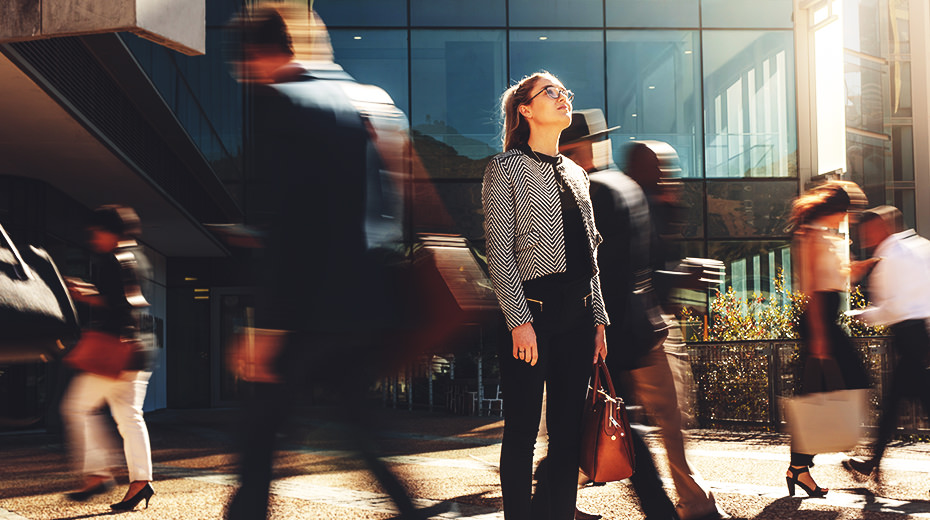 Woman looking up surrounded by blurred passerby's as she considers the brand promise of her company.