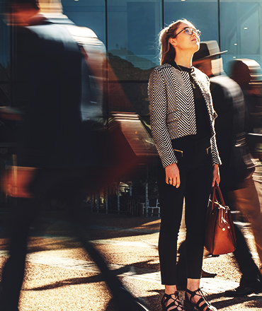 Woman looking up surrounded by blurred passerby's as she considers the brand promise of her company.