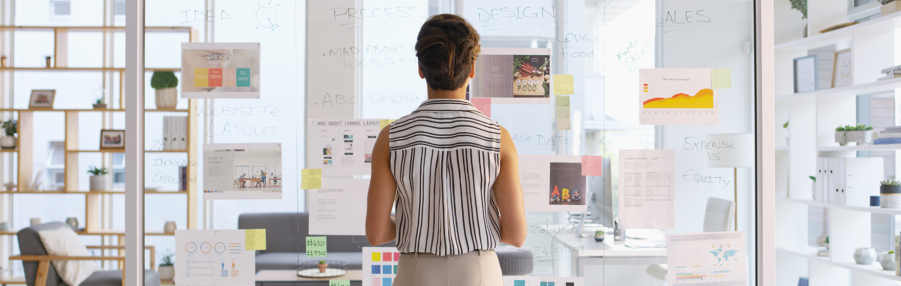 Rearview shot of a businesswoman writing down ideas on a glass wall in her office