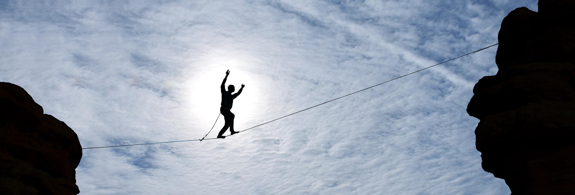 an upward shot of a person tight rope walking over a canyon